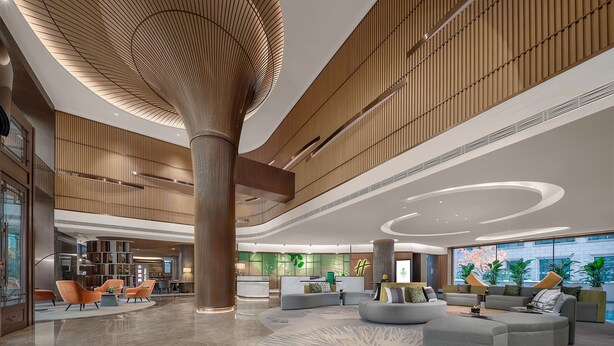 A spacious lobby with a central column, seating areas, and a reception desk. - Holiday Inn Changchun Jingyue by IHG (Changchun)