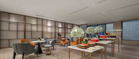 A modern dining area with a high ceiling, recessed lighting, and a large window providing natural light.