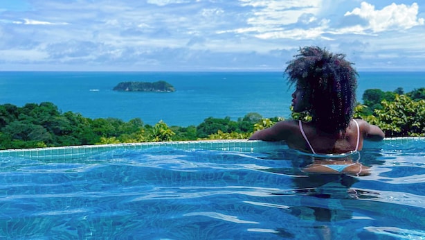 A person in a swimming pool with a view of the ocean and an island. - Villa Roca Boutique Resort & Suites-ADULT ONLY (Quepos)