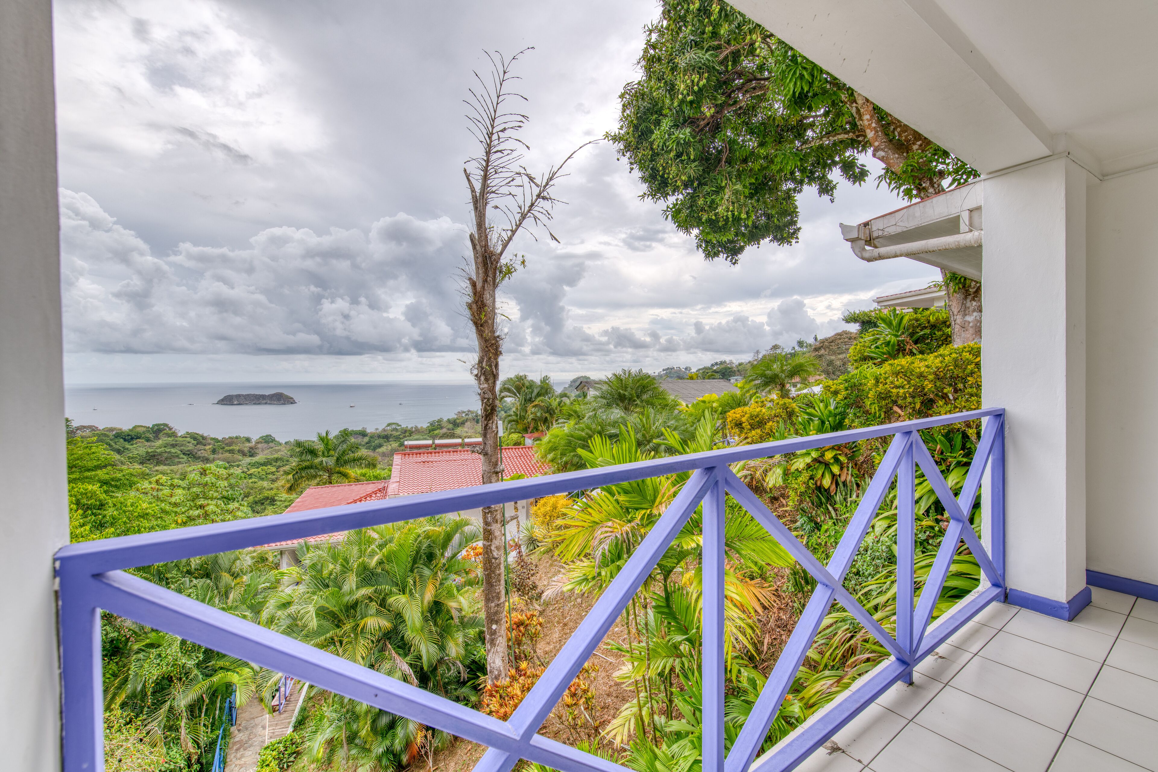 Un balcon offrant une vue sur un paysage luxuriant et la mer.