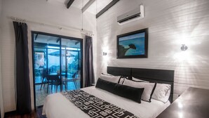 A hotel room with a large bed, a view of the outdoors, a dining area, and a framed picture on the wall. - Villa Roca Boutique Resort & Suites-ADULT ONLY (Quepos)