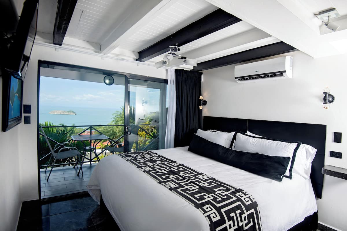 Un hotel moderno con una cama grande, un balcón con vistas y un equipo de aire acondicionado en la pared.