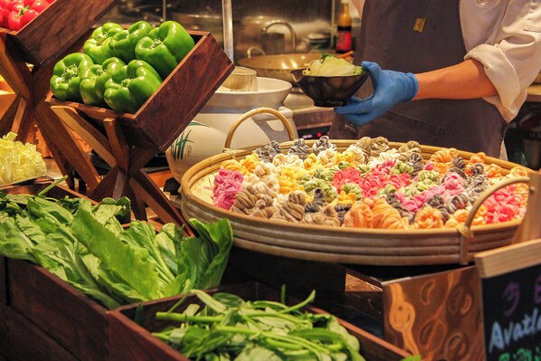Exhibición de alimentos con diversas verduras y una persona usando guantes.