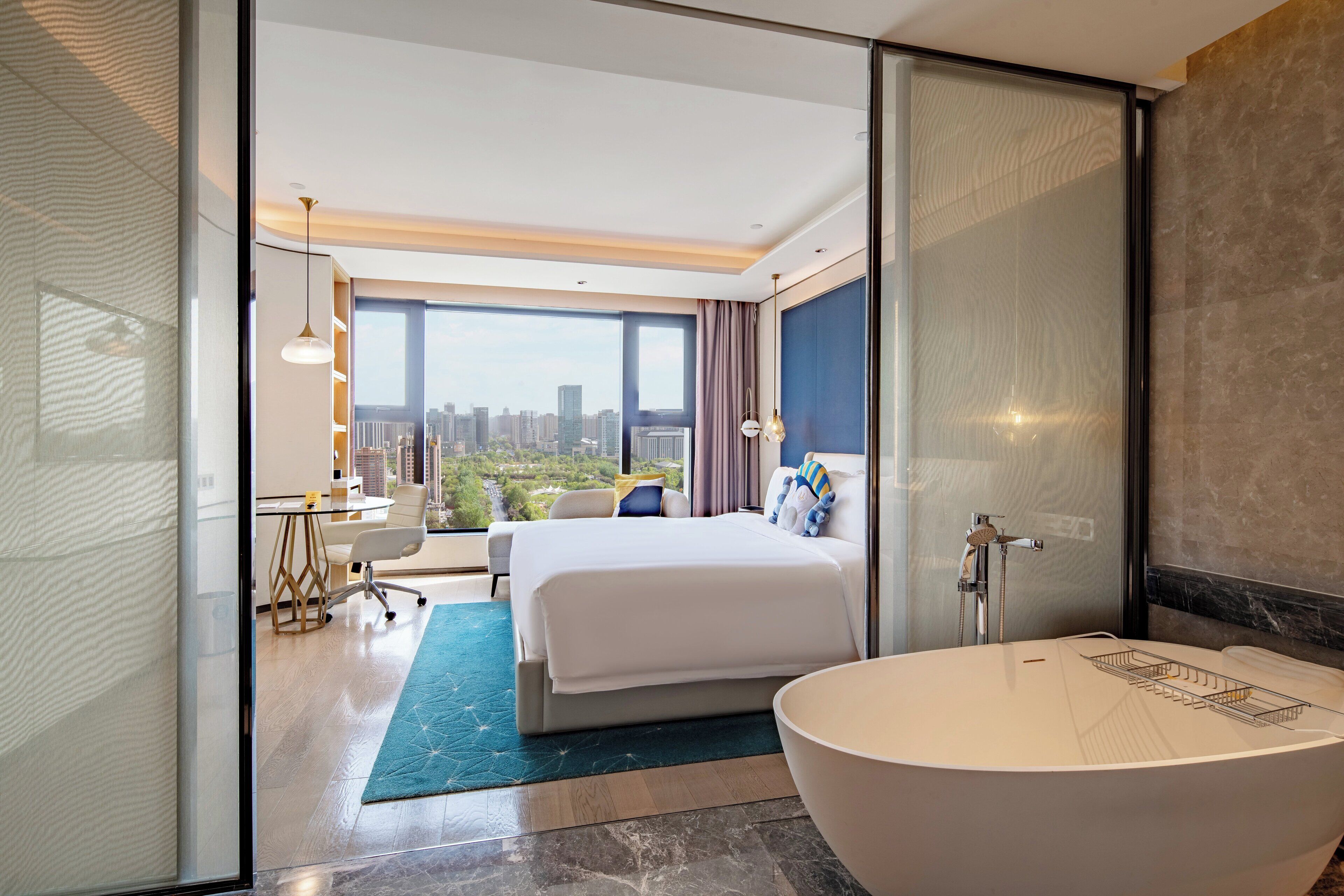A modern hotel room with a large bed, a bathtub, and a city view.