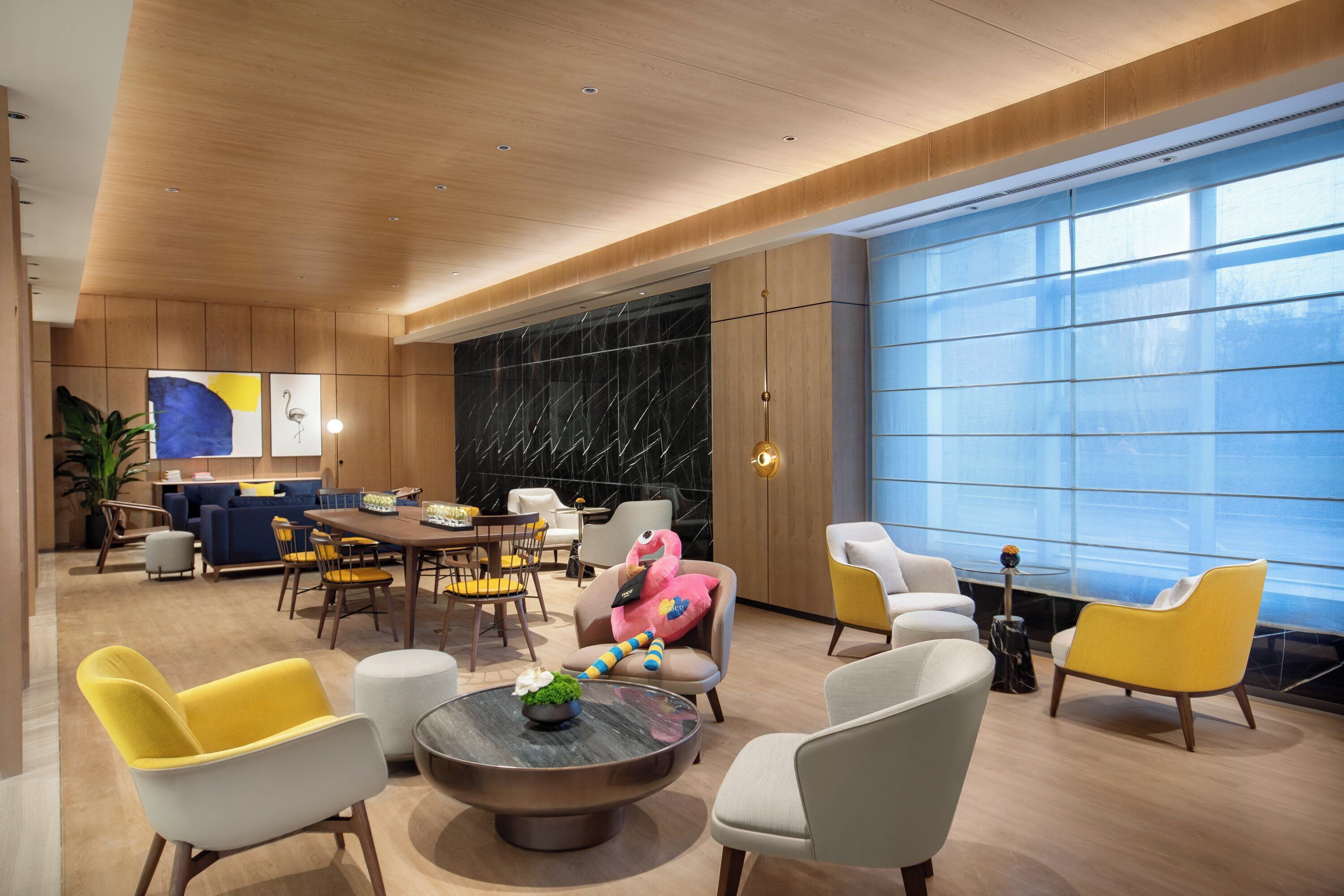 A modern interior with a dining area, seating, and large windows.