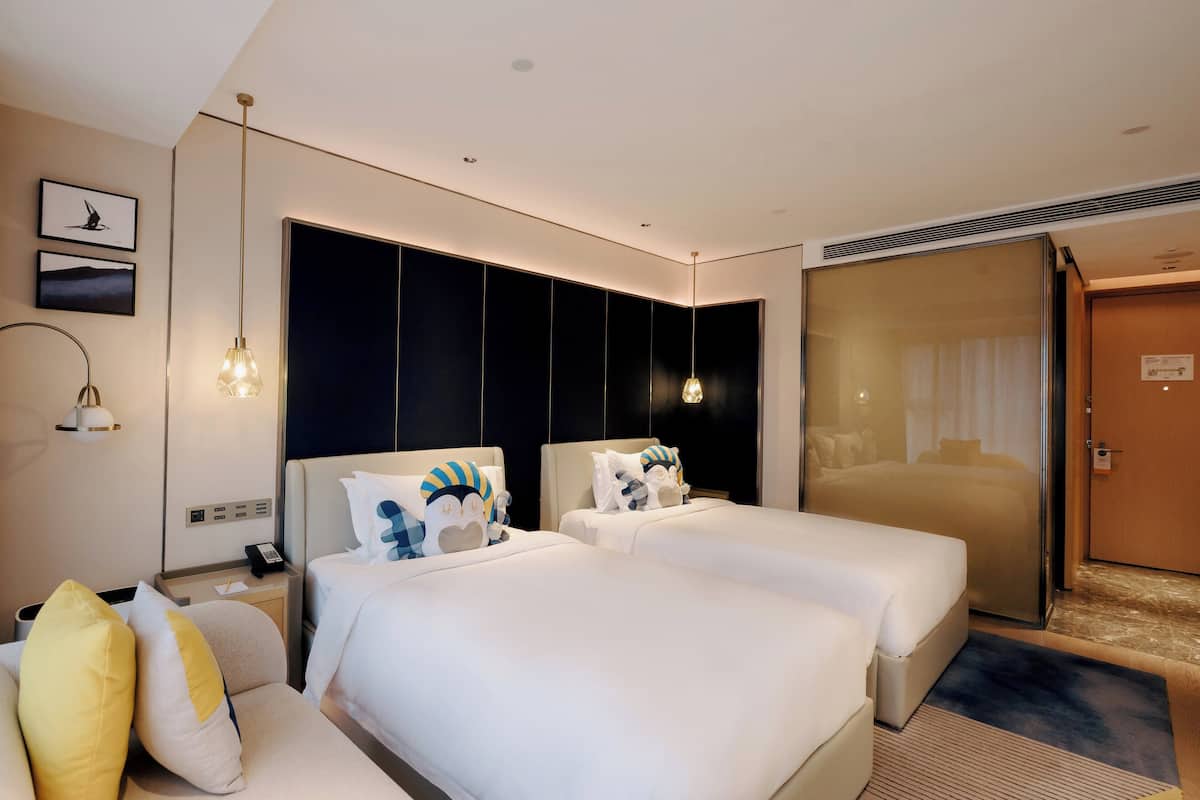 A hotel room with two beds, a sofa, a desk, and a mirror.