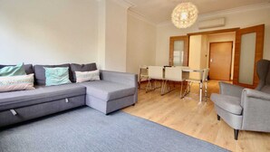 A modern living room with a grey sectional sofa, a dining table with chairs, and a grey armchair.