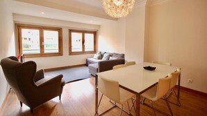 A modern living room with a dining table, two sofas, and a large window.