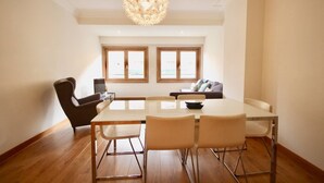 A dining area with a large table and chairs, a sofa, and a TV.