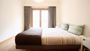 A bedroom with a bed, curtains, a nightstand, and a chandelier.