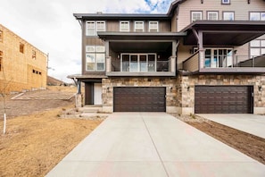 A two-story residential building with a stone facade, a covered front porch, and a garage.
