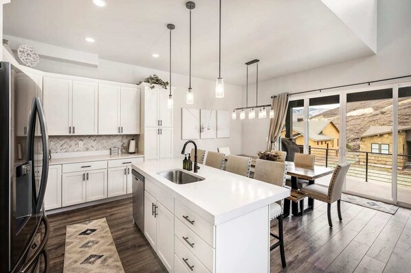 A modern kitchen with white cabinetry, a large island with a sink, and pendant lighting.