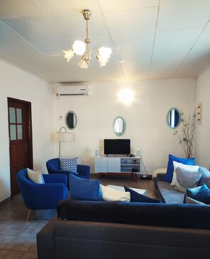 Relax in this stylish living room with a sofa, armchairs, and a flat-screen TV.
