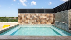 A rectangular swimming pool with a tiled wall featuring a mosaic pattern.