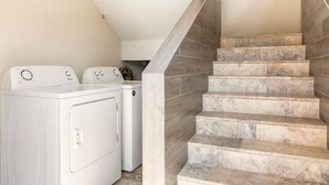 A laundry area with two white washing machines and a staircase with grey stone steps.