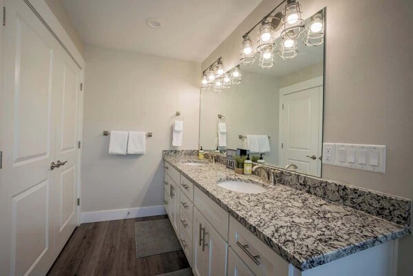 A bathroom with a double sink vanity, a large mirror, and a light fixture above the mirror.