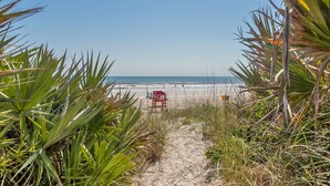A pathway leading to a beach with a lifeguard chair visible in the distance. - DIRECT OCEANFRONT BEACH HOME! PRIVATE BEACH ACCESS! (New Smyrna Beach)
