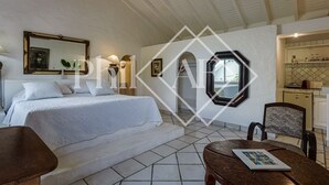 A bedroom with a bed, a desk, a chair, and a small table. There is a window with a view of the outside. - Exceptional Villa Anse Marcel (Anse Marcel)