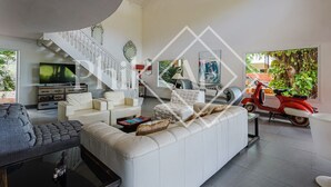 A modern living room with a white sofa, a TV, and a red scooter. - Exceptional Villa Anse Marcel (Anse Marcel)