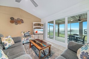 A living room with a view of the ocean, a wooden coffee table, gray sofas, and a patterned armchair.