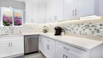 Enjoy cooking in this well-equipped kitchen with a dishwasher, coffee maker, and mosaic tile backsplash.