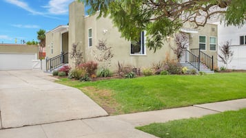 Welcome to this charming two-story home with a beautifully landscaped yard and a staircase leading to the upper level.