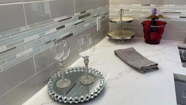 Eine Küche mit Marmorarbeitsplatte, einem Weinkühler aus Glas und einem roten Champagnerkübel.