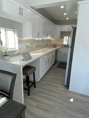 A modern kitchen with white cabinets, a marble countertop, and a laptop on the island. - One bedroom new remodel furnished to tens! Pure luxury, professionally decorated (Los Angeles)