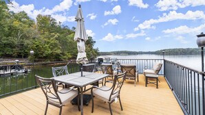 A deck with outdoor furniture, a view of the lake, and a dock with boats. - Lakefront Luxury Cabin Retreat with Jacuzzi & Party Dock (Gainesville)