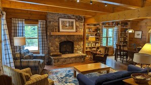 A cozy living room with a stone fireplace, a bookshelf, and a comfortable seating area.