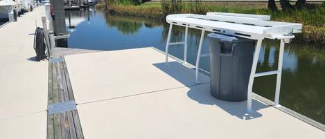 A dock with a white trash bin and a metal railing.