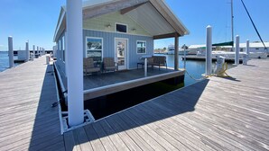 A docked boat with a covered deck, seating area, and a small window.