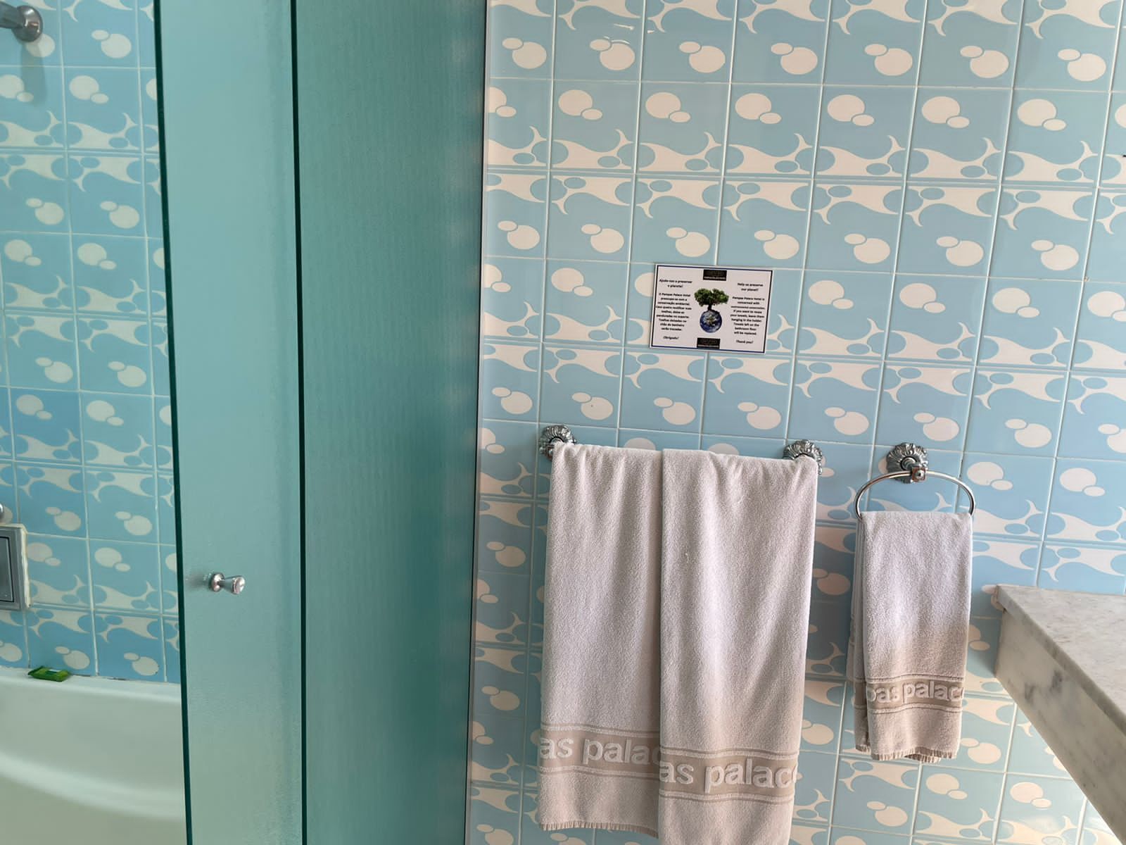 A bathroom with teal walls, a bathtub, and two towels hanging on a rack.