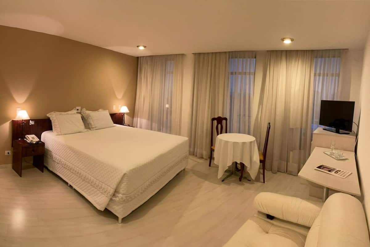 Une chambre d’hôtel avec un grand lit, des lampes de chevet, une table ronde, une chaise et un téléviseur.