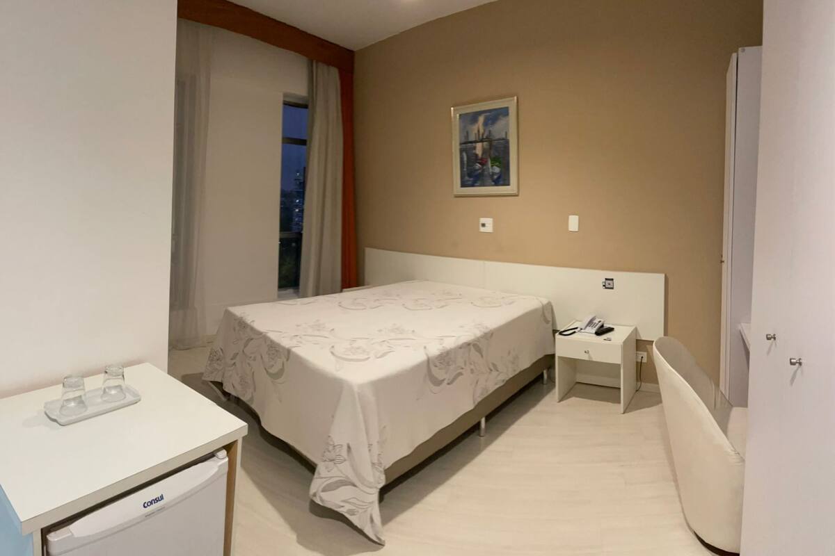 Une chambre à coucher avec un lit, une table de chevet et un bureau avec un téléphone.