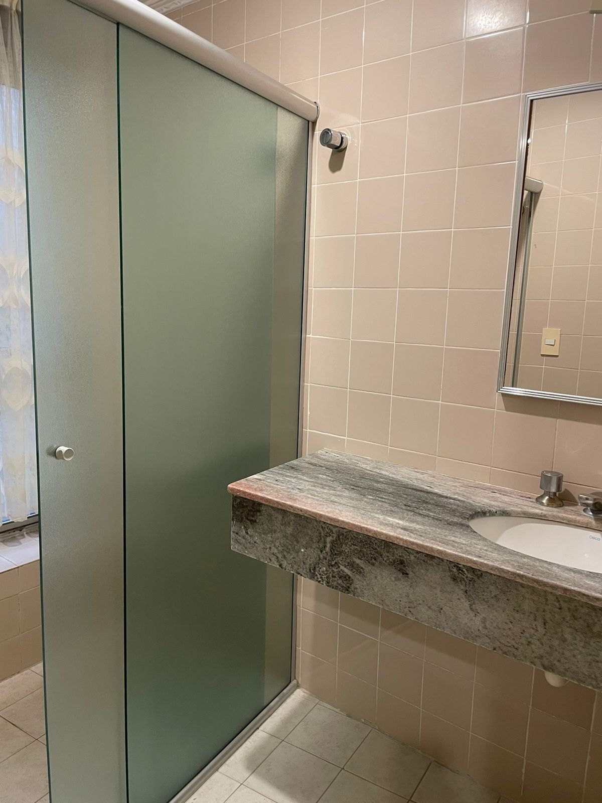 Un baño con un mueble verde, una encimera de mármol y un espejo.