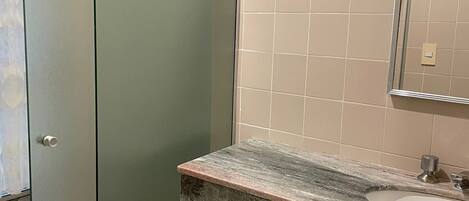 Un baño con un mueble verde, una encimera de mármol y un espejo.