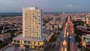 A high-rise hotel with multiple floors, a prominent entrance, and a view of the cityscape in the background. - DoubleTree by Hilton Manisa (Manisa)