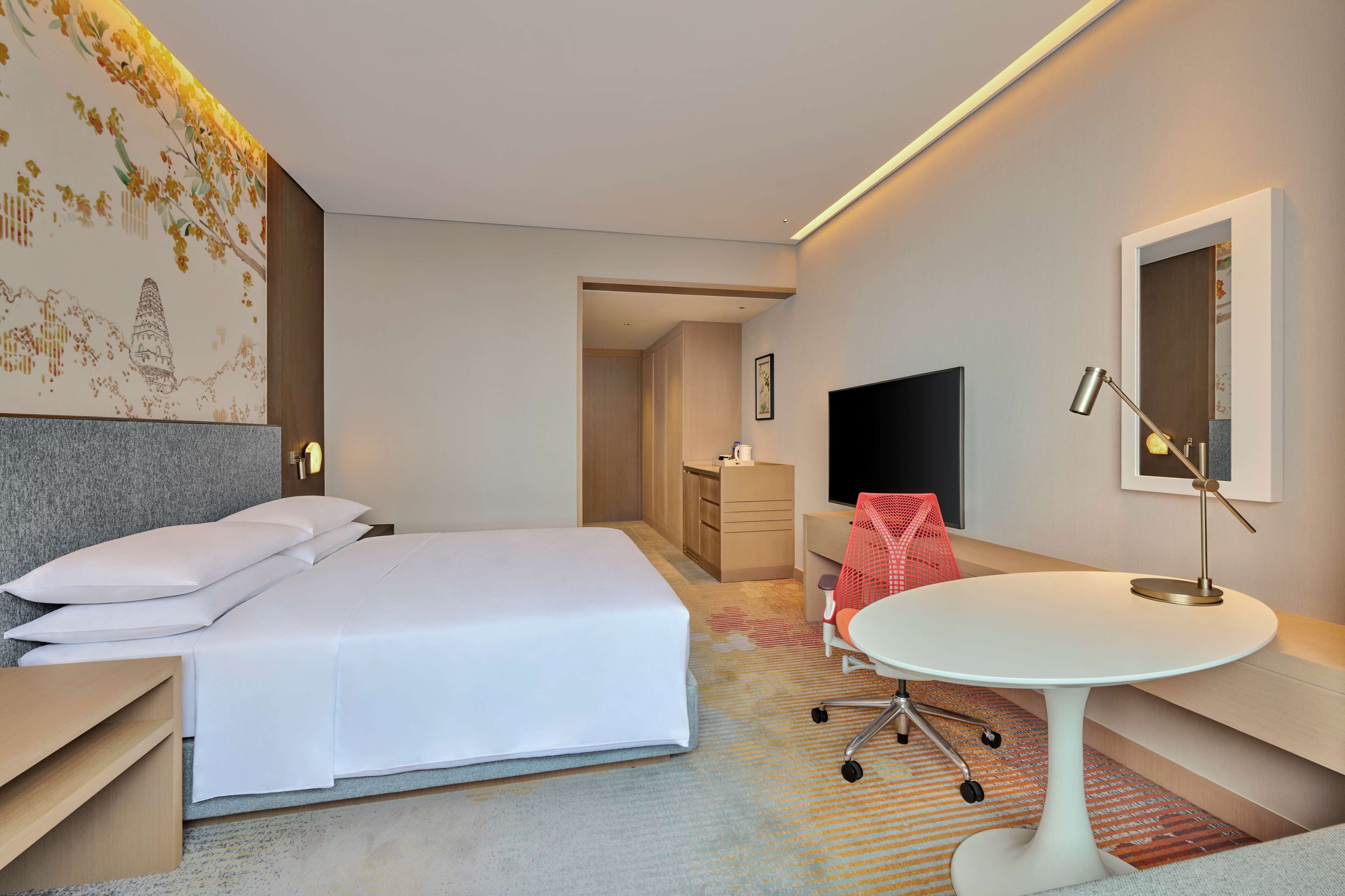 Une chambre d’hôtel comprenant un lit, une table de chevet, un bureau, une chaise et un téléviseur.