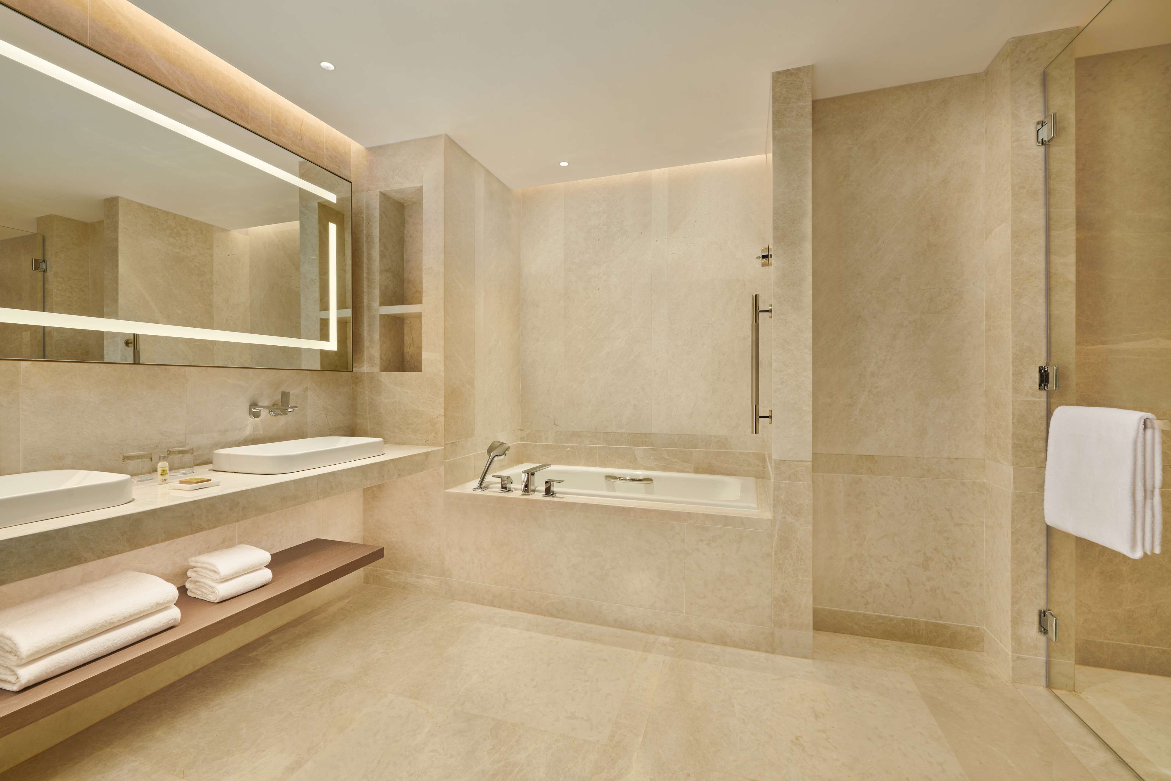 Un baño moderno con dos lavamanos, una bañera y una cabina de ducha de vidrio.