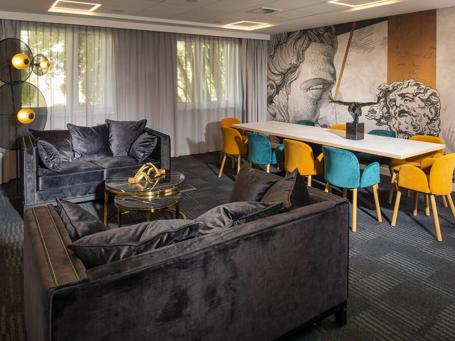 Uma sala de reuniões moderna com um sofá, cadeiras, uma mesa e um grande mural abstrato.