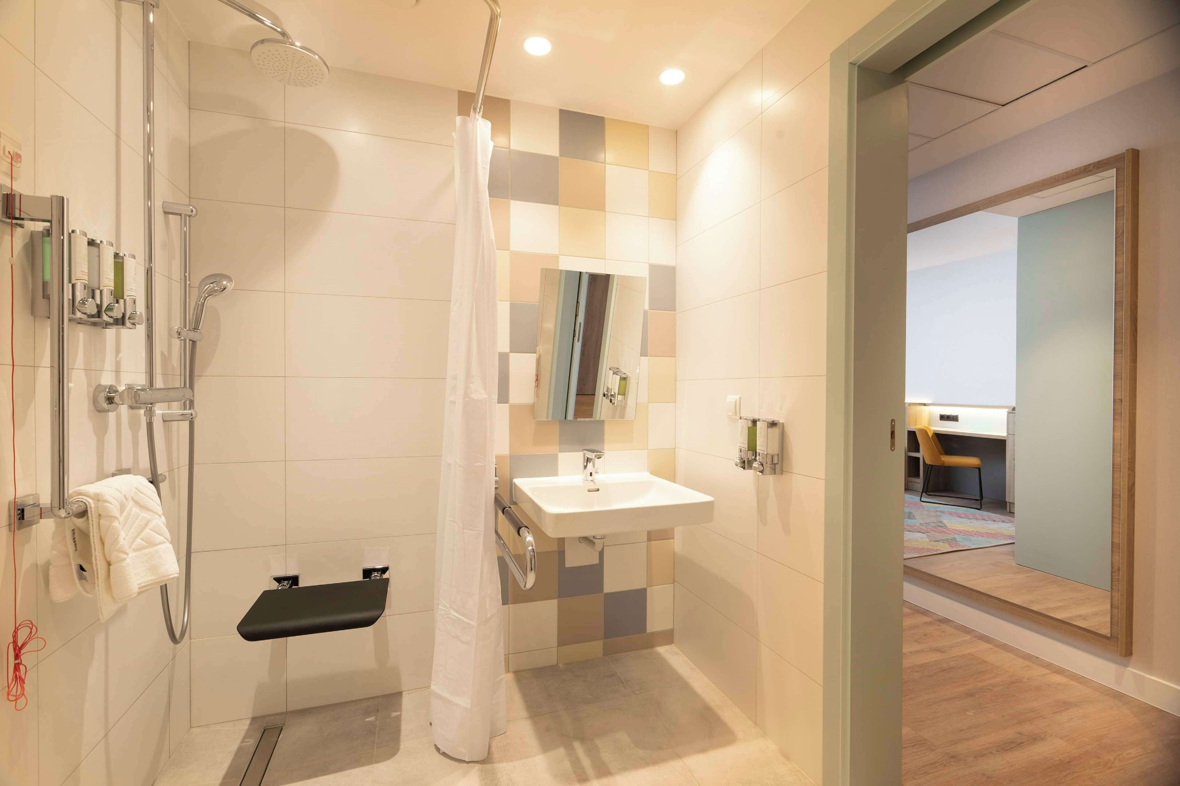Ein modernes Badezimmer mit Dusche, Waschbecken und einer kleinen Sitzbank.