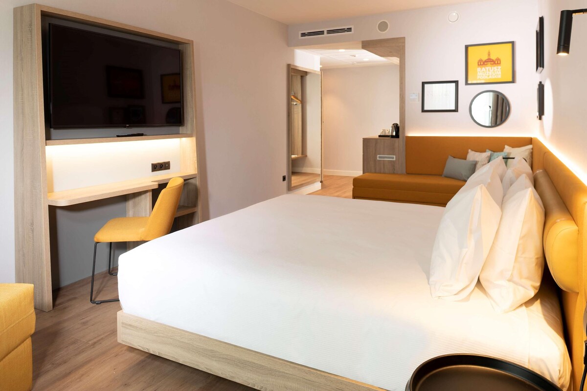 Una habitación de hotel con una cama, un escritorio, una silla y un armario.