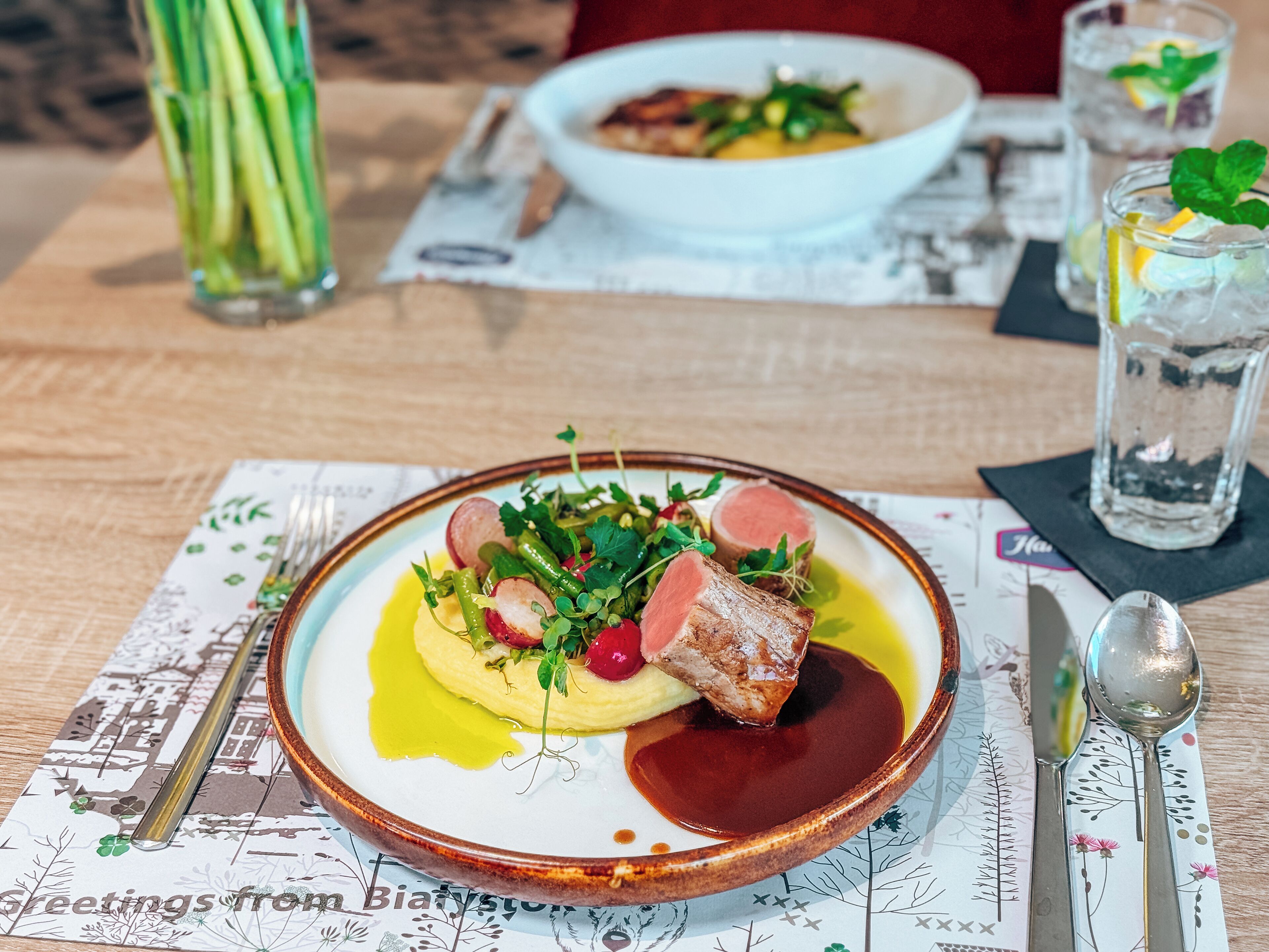 Une table à manger avec une assiette de nourriture, un verre d’eau et un menu.