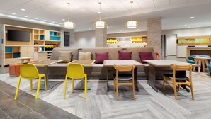 A modern interior with a seating area, tables, and a kitchen in the background.