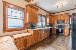 Una cocina con gabinetes de madera, un microondas integrado, una estufa y un banco.