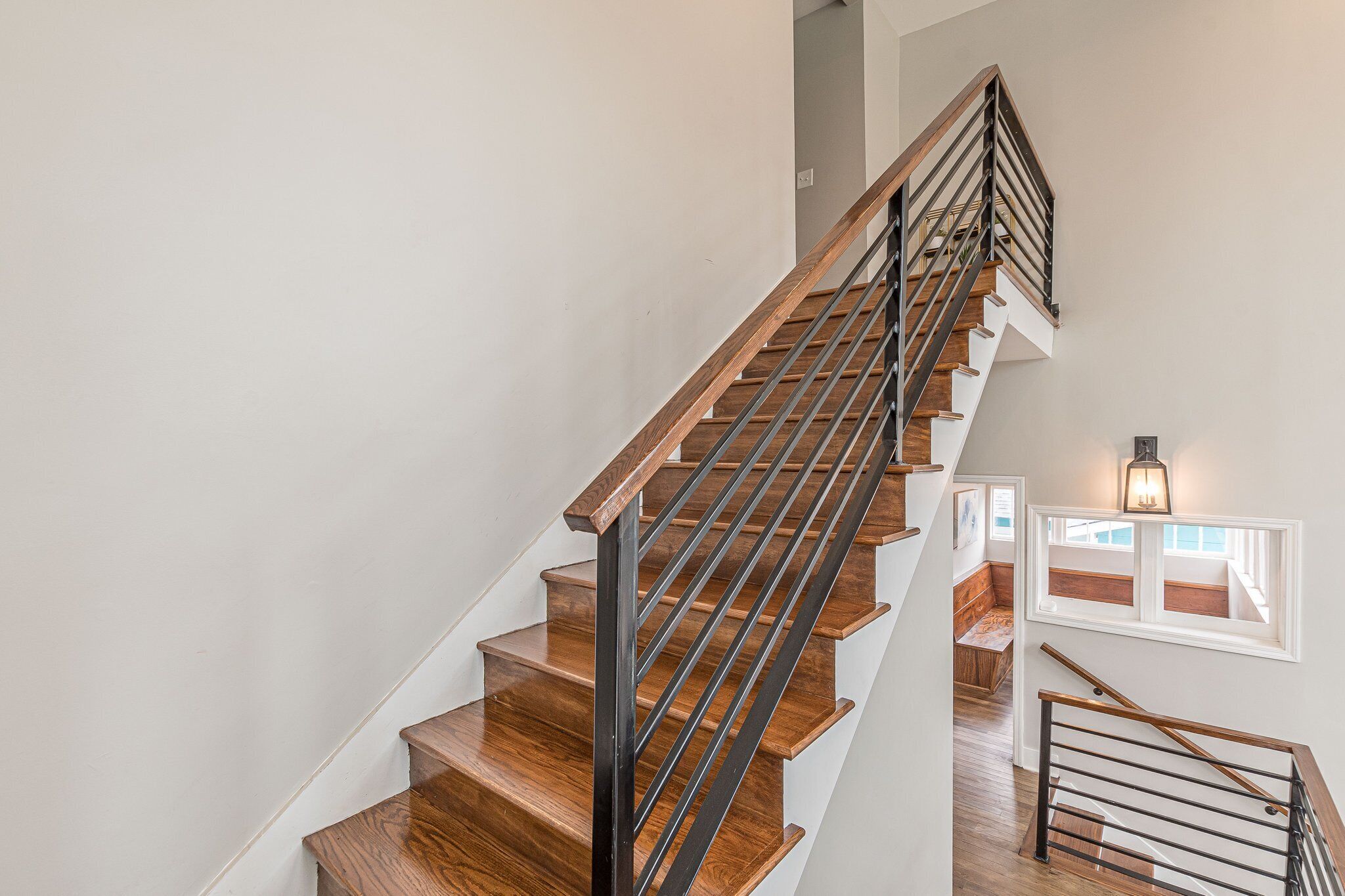 Eine Treppe mit Holzboden und Metallgeländern, die zu einer oberen Etage führt.