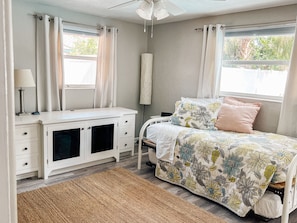 A bedroom with a bed, a nightstand, a desk, and a window with curtains. - The Coral Cottage close to all that Sarasota has to offer (Sarasota)