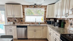 A kitchen with white cabinets, a dishwasher, a microwave, and a coffee maker. - The Coral Cottage close to all that Sarasota has to offer (Sarasota)