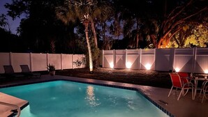 A swimming pool with a white fence, lounge chairs, and a table with chairs. - The Coral Cottage close to all that Sarasota has to offer (Sarasota)